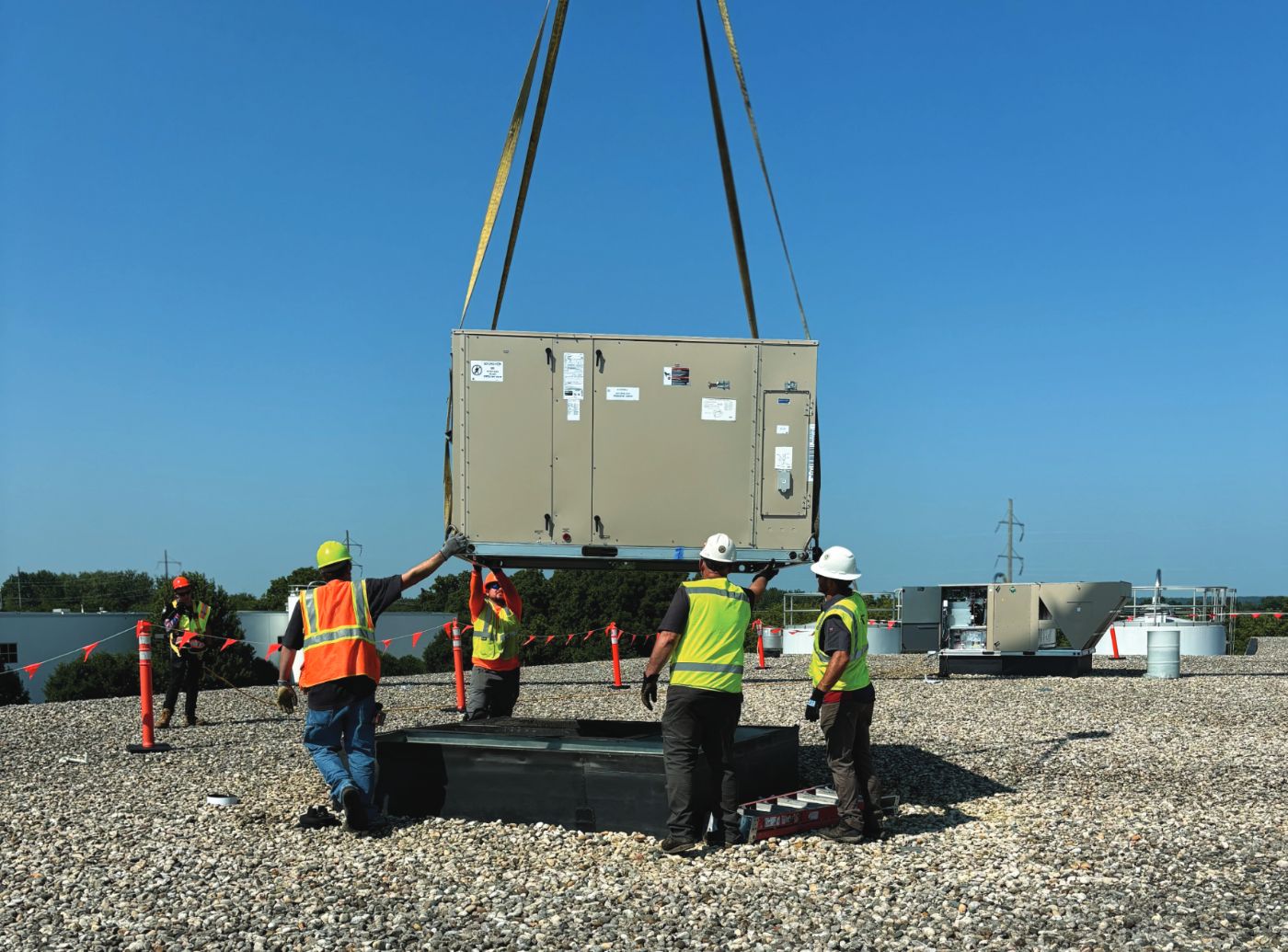 Rabine crew landing a rooftop unit from a crane